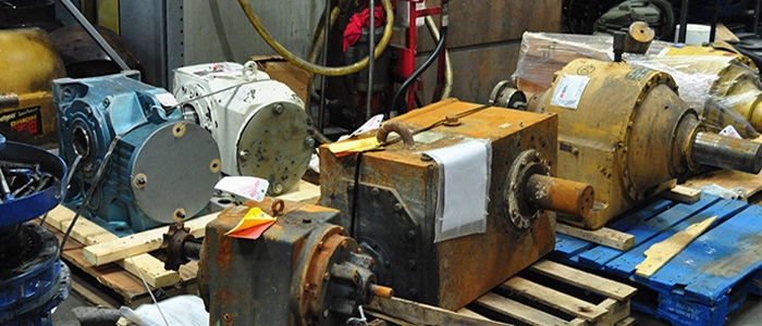 Numerous industrial motors and rotating equipment on wooden pallets lined up for repair and re-manufacture