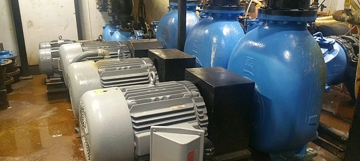 Row of five gray and blue process pumps in facility